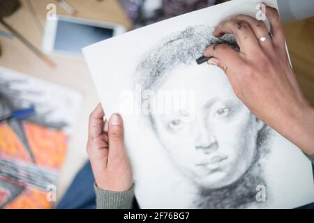 Vue de dessus d'un gros plan des mains d'une personne dessinant un portrait au charbon de bois sur une toile. Concept des classes de peinture. Mise au point sélective. Espace pour te Banque D'Images