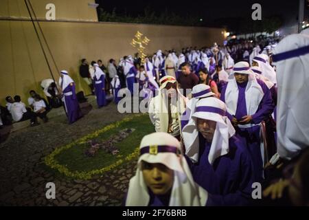 Les Cucuruchos en robes violettes se déroulent solennellement dans les rues d'Antigua, au Guatemala, pendant les célébrations traditionnelles de la semaine Sainte de Semana Santa. Banque D'Images