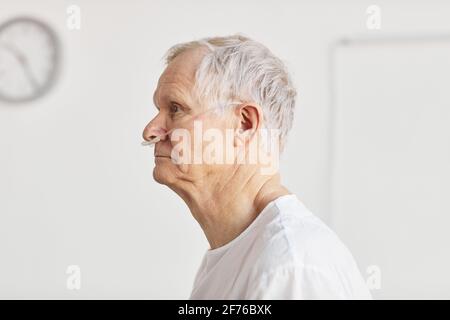 Portrait de l'homme âgé à l'hôpital avec vue latérale et accent sur les tubes de support d'oxygène, espace de copie Banque D'Images