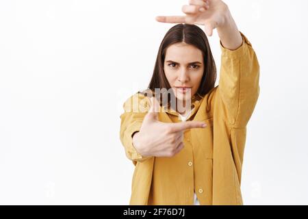 Femme créative et passionnée à la recherche d'un angle parfait, regardant à travers les cadres de la main mouvement de caméra et le regard pensif déterminé, créant quelque chose Banque D'Images