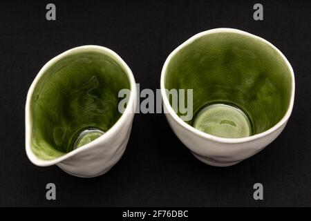 Tasse et verseuse en céramique blanc avec vert intérieur photographié sur fond noir Banque D'Images