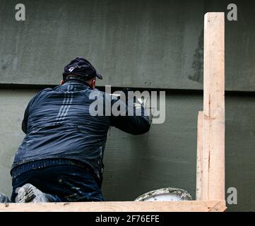 Dnepropetrovsk, Ukraine - 03.30.2021: Ouvrier de façade plâtrage mur extérieur de bâtiment. Banque D'Images