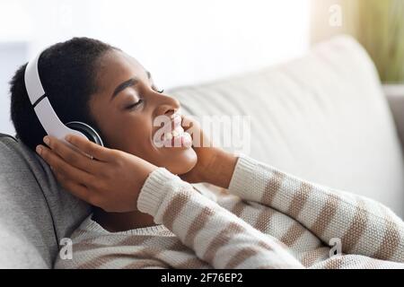 Le temps de se détendre. Jeune femme noire positive dans un casque sans fil Ecoute de la musique Banque D'Images