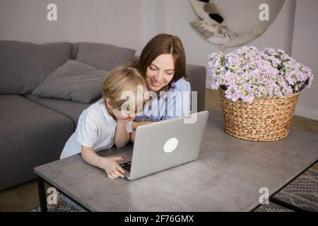 Restez à la maison. Mère et fils à un ordinateur portable, formation en ligne, aider un enfant à maîtriser les technologies numériques modernes. Un passe-temps intéressant à la maison pendant un lo Banque D'Images