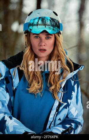 Femme snowboarder en costume brillant dans des lunettes de sport tient un snowboard. Sports extrêmes. Loisirs Banque D'Images