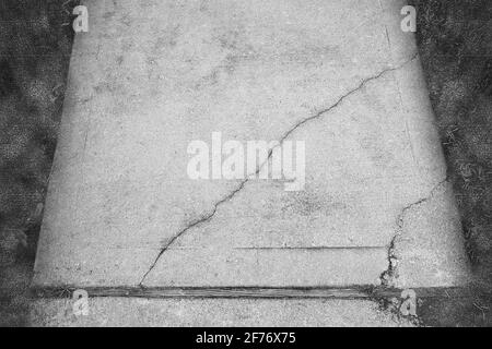 Photographie abstraite en noir et blanc d'un trottoir en béton fissuré et brisé où les fissures sont mises en évidence et sont le principal intérêt. Banque D'Images