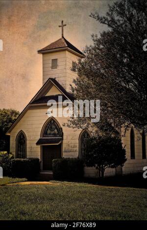 Vue d'angle d'une église en bois blanc avec un clocher blanc avec une croix sur le dessus du clocher. Photographié sur les routes arrière du Texas. Banque D'Images
