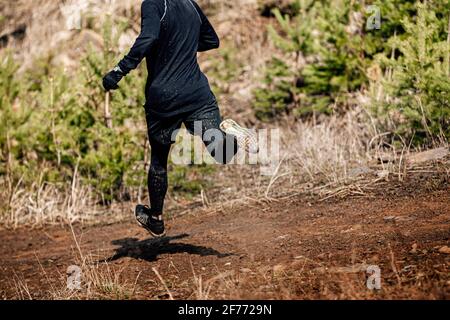 un jogging mâle descend la montagne sur un sentier boueux Banque D'Images