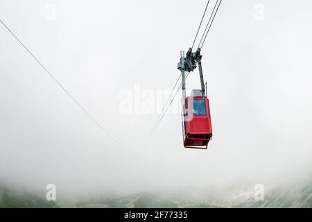 Funiculaire rouge ou téléphérique de suspension rouge jusqu'au pic Lomnicky dans le brouillard ou les nuages, High Tatry, Slovaquie Banque D'Images