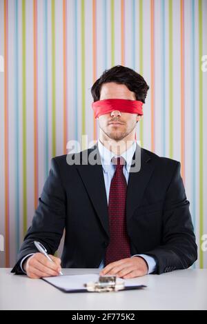 Homme d'affaires aveuglément à son bureau signant des contrats Banque D'Images