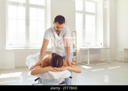 Masseuse ou thérapeute manuel effectuant un massage relaxant du corps pour les jeunes femme allongée sur une table de massage Banque D'Images