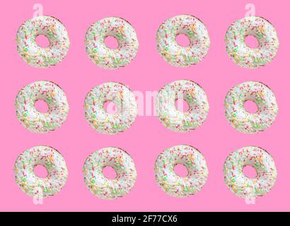 Motif composé de beignets en anneau avec glaçure blanche et de centaines et de milliers de courgeuses sur fond rose Banque D'Images