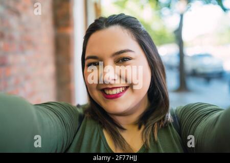 Jeune femme de taille plus prenant un selfie. Banque D'Images