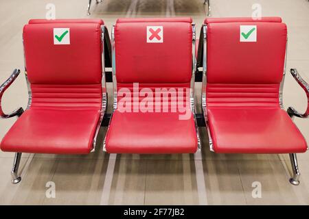 Rangée de trois sièges en cuir rouge vides à l'intérieur du salon du grand aéroport contemporain où vous pouvez vous asseoir, vous détendre ou dormir tout en attendant le vol Banque D'Images