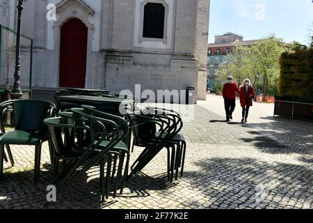 Deux personnes portant un masque de protection marchent près d'un autre espace vers des restaurants encore fermés dans le quartier de Graça, Lisbonne. Au cours du Conseil des ministres, une décision de lever certaines mesures d'urgence a été prise, après avoir analysé la situation de la pandémie COVID-19 au Portugal. La deuxième phase au Portugal permet aux restaurants avec terrasses de rouvrir ces espaces en plein air, mais avec des groupes limités à un maximum de quatre personnes. Banque D'Images