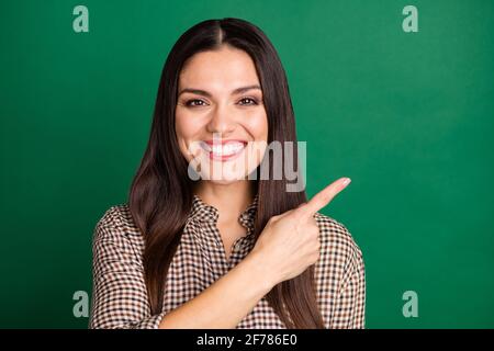 Photo d'une jolie dame gaie indique l'usure de l'espace vide du doigt chemise à carreaux avec fond vert isolé Banque D'Images