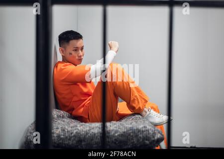 Criminel asiatique avec tatouages sur son visage dans une cellule repents du crime. Dépression d'un prisonnier en prison Banque D'Images