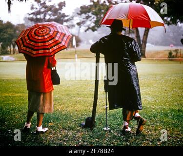 COUPLE DES ANNÉES 1970 HOMME ET FEMME D'ÂGE MOYEN PORTANT DES MANTEAUX DE PLUIE GOLF À CRAMPONS CHAUSSURES DEBOUT SOUS LES PARASOLS SUR LE TERRAIN DE GOLF EN PLUIE - KS6369 HAR001 SATISFACTION DU SARS FEMMES ÉPOUSÉES CONJOINT RURAL ÉPOUX SAINTETÉ COPIE ESPACE PLEINE LONGUEUR DAMES PLUVIEUX PERSONNES MÂLES PARAPLUIES GOLF PLUIE ATHLÉTIQUE SPECTATEURS PARTENAIRE DE LA GALERIE D'ÂGE MOYEN PARCOURS D'AMUSEMENT D'ACTIVITÉ D'HOMME D'ÂGE MOYEN BONHEUR FEMME D'ÂGE MOYEN BIEN-ÊTRE AVENTURE GOLFEURS HOBBY LOISIR INTÉRÊT ET CHOIX PASSE-TEMPS SAVOIR LOISIRS PASSE-TEMPS PLAISIR CONCEPTUEL RETARD LIENS ÉLÉGANT SOUTIEN IMPERMÉABLE FANS RELAXATION ÉPOUSES AMATEUR Banque D'Images