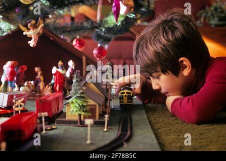 ANNÉES 1970, UN GARÇON ENGROSSÉ JOUANT AVEC LE TRAIN MODÈLE DE JAUGE HO SOUS L'ARBRE DE NOËL ENTOURANT UNE SCÈNE DE NATIVITÉ MANGER - KX8880 DAS001 HARS ANGEL CÉLÉBRATION ACCUEIL VIE COPIE ESPACE HOMMES ANGES RAIL RÊVES TÊTE ET ÉPAULES MERRY RÉCRÉATION UN CALIBRE MANGER DÉCEMBRE CONNEXION ENGROSED ENTOURANT DÉCEMBRE 25 IMAGINATION CAPTIVÉE CHEMINS DE FER CRÉATIVITÉ CRECHE FOCALISÉ HO JOYEUX JUVÉNILES ABSORBAIENT L'ETHNIE CAUCASIENNE ANCIENNE RAILS À LA MODE Banque D'Images