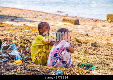 Île de Wasini, Kenya, AFRIQUE - 26 février 2020 : les enfants africains s'assoient sur une pile de déchets lavés par la mer et attendent les touristes. Banque D'Images