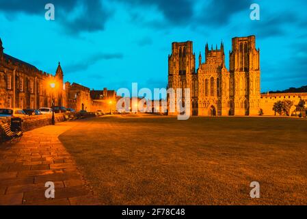 Wells Cathedral dans le Somerset Angleterre avec des lumières orange illuminant le Avant ouest de la structure gothique et du début de l'anglais vert à l'avant Banque D'Images