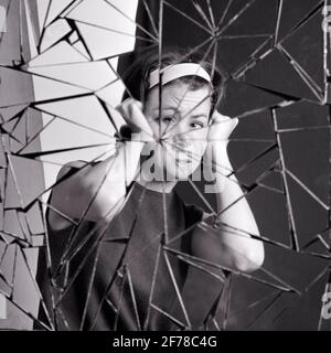 ANNÉES 1960, LES ANNÉES 1970 ONT PERTURBÉ LA FEMME REGARDANT LA CAMÉRA TENIR LA TÊTE DEDANS DOULEUR VOYANT SA RÉFLEXION DANS DES ÉCLATS DE VERRE BRISÉ DE MIROIR - S19061 HAR001 HARS STUDIO SHOT MOODY MALADIE VIE À LA MAISON ESPACE DE COPIE DEMI-LONGUEUR RISQUE MALADIE NERVEUSE SYMBOLES EXPRESSIONS B&W TROUBLÉ INQUIET TRISTESSE MALADIE CONTACT OCULAIRE SOINS DE SANTÉ ANXIÉTÉ CATASTROPHE RÊVES SOUFFRANCE PRÉVENTION DE LA PERSONNALITÉ DÉCOUVERTE GUÉRISON DIAGNOSTIC COMBINÉ DÉSESPOIR SANTÉ DANS DE VOIR LA DÉFICIENCE DE TRAITEMENT DE L'HUMEUR CONCEPT DE SANTÉ MENTALE GLUM CONCEPTUEL ÉCHAPPER À L'IMAGINATION MAUVAISE SANTÉ TENSION SYMBOLIQUE MAUVAIS CONCEPTS DÉSORDRE MISÉRABLE DOULOUREUX Banque D'Images