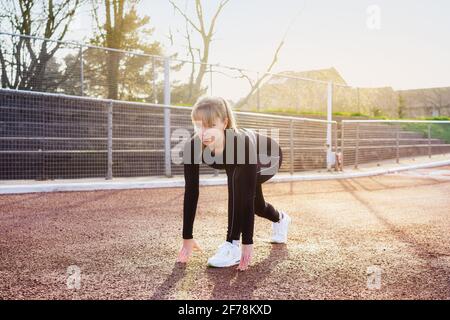 Femme se prépare à courir dans le stade. Entraînement en plein air. Jogging dans le stade. Lumière du coucher du soleil. Mode de vie actif, sport et soins de santé. Copier Banque D'Images