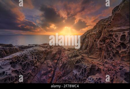 Mer au coucher du soleil et rochers érodés par le vent dans la falaise de Populonia Buca delle Fate. L'île d'Elbe à l'horizon. Paysage en Maremme. Piombino, Toscane, IT Banque D'Images