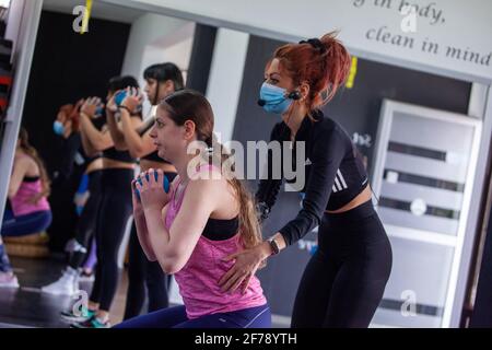 Nicosie, Chypre. 5 avril 2021. Un entraîneur portant un masque facial aide un client avec ses exercices dans un gymnase rouvert à Nicosie, Chypre, le 5 avril 2021. L'entraînement sportif individuel a repris à Chypre depuis vendredi dernier. Sept personnes maximum sont autorisées dans les salles de sport et les piscines publiques. Credit: George Christophorou/Xinhua/Alay Live News Banque D'Images