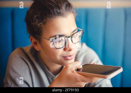 Femme en lunettes enregistrant un message audio vocal avec mobile téléphone Banque D'Images