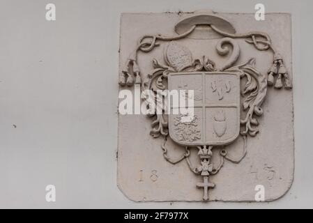 L'ancienne blason de 1843 sur le mur de la maison. Armoiries avec chapeau papal, croix et plantes. Banque D'Images