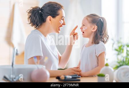 Bonne famille ! La mère et la fille enfant fille s'occupent de la peau dans la salle de bains. Banque D'Images