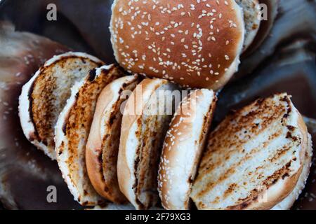 Petits pains de hamburger grillés aux graines de sésame dans un bol en métal. Banque D'Images