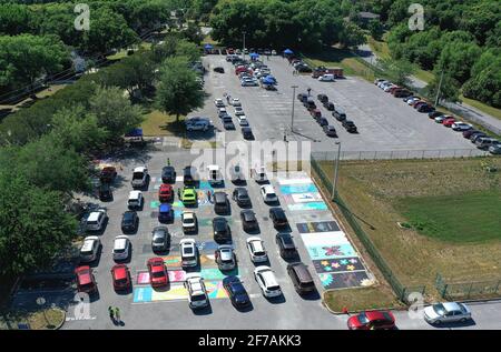 Eustis, États-Unis. 05 avril 2021. (NOTE DE LA RÉDACTION: Image prise avec drone) les étudiants font la queue dans les voitures pour recevoir une photo du vaccin Pfizer-BioNTech sur un site de vaccination au drive COVID-19 à l'école secondaire d'Eustis le premier jour où Floridians 16 et plus sont devenus admissibles à la vaccination. Quatre autres écoles secondaires du comté de Lake accueilleront des sites semblables de vaccination d'une journée cette semaine. Crédit : SOPA Images Limited/Alamy Live News Banque D'Images