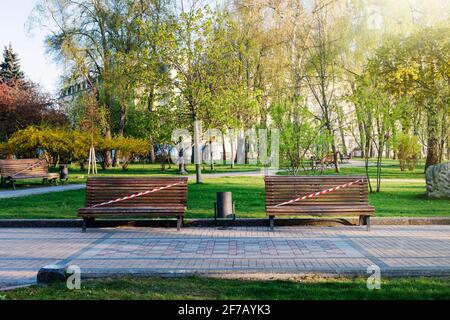 Kiev, Ukraine, parc municipal vide pendant la quarantaine 2021. La visite des parcs est interdite, les bancs sont fermés par un ruban rouge et blanc. Banque D'Images