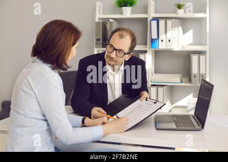 Une femme signe un contrat assis à son bureau dans le directeur de banque ou bureau de l'agent d'assurance Banque D'Images