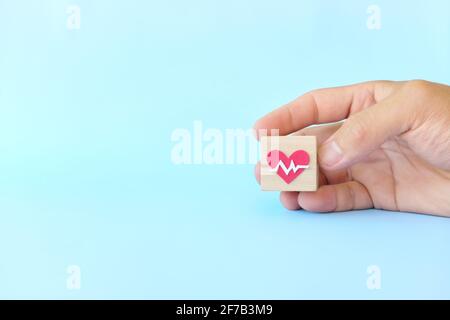 Icône de pulsation de soins de santé de choix main sur des blocs de bois avec espace de copie. Santé priorité et concept d'assurance médicale. Banque D'Images