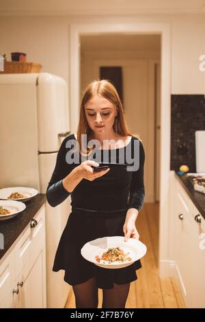Femme en cuisine prenant la photo de la nourriture sur l'assiette Banque D'Images