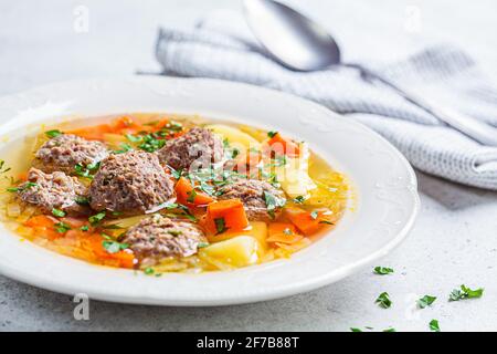 Soupe de boulettes de viande maison avec légumes dans une assiette blanche, fond gris. Concept alimentaire confort. Banque D'Images