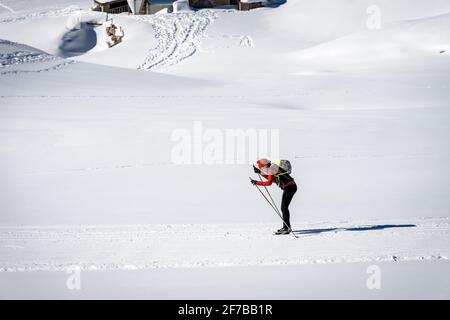 Skieur de fond féminin sur une piste par une journée ensoleillée sur le plateau de Lessinia, station de ski de Malga San Giorgio, province de Vérone, Vénétie, Italie, Europe. Banque D'Images