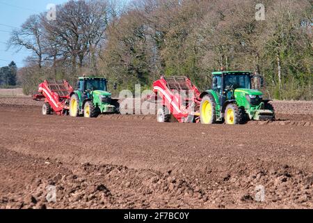 Deux tracteurs John Deere remorquant les séparateurs Grimme CS150, en enlevant les pierres et autres matériaux des lits de plantation de pommes de terre dans un champ à Wirral, au Royaume-Uni Banque D'Images