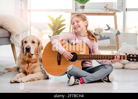 Petite fille avec guitare et chien Golden Retriever Banque D'Images