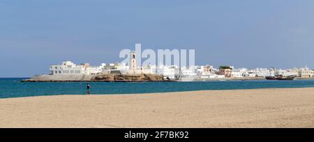 Un jogging sur la plage de sur, le village d'Ayjah de l'autre côté du lagon. Oman. Banque D'Images