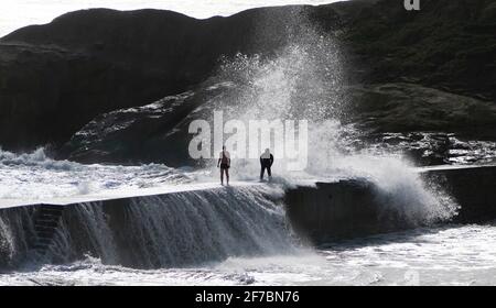 Les gens essaient d'éviter que les vagues ne s'écrasant sur les murs de Cullercoats près de Tynemouth. Date de la photo: Mardi 6 avril 2021. Banque D'Images