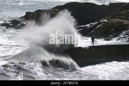 Les gens essaient d'éviter que les vagues ne s'écrasant sur les murs de Cullercoats près de Tynemouth. Date de la photo: Mardi 6 avril 2021. Banque D'Images