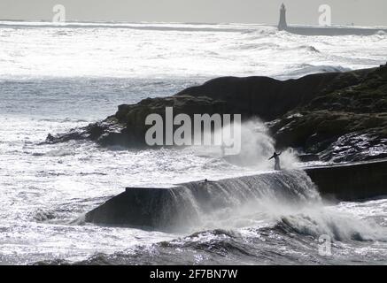 Les gens essaient d'éviter que les vagues ne s'écrasant sur les murs de Cullercoats près de Tynemouth. Date de la photo: Mardi 6 avril 2021. Banque D'Images