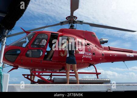 Un hélicoptère AS350 Squirrel, exploité par Nautilus Aviation, survole le récif Hastings, dans la mer de Corail, à 30 milles marins de Cairns Banque D'Images