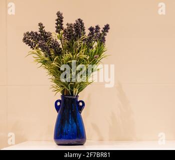 Lavande dans un vase en verre bleu sur un fond calme. Banque D'Images