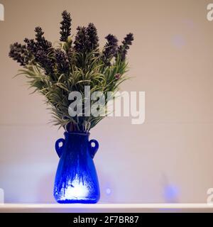 Lavande illuminée dans un vase en verre bleu. Design intérieur de haute qualité. Banque D'Images