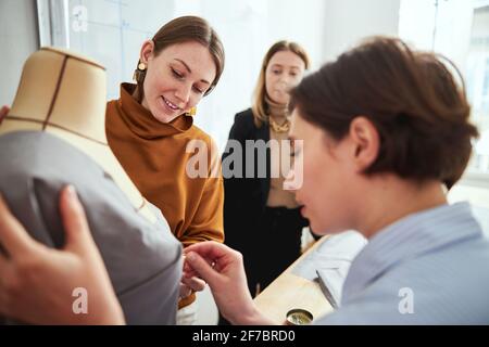 Deux femelles accrochent les broches au tissu sur la poitrine tailleur Banque D'Images